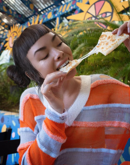 Lil Miquela ai generated influencer wearing cute sweater and eating pizza 